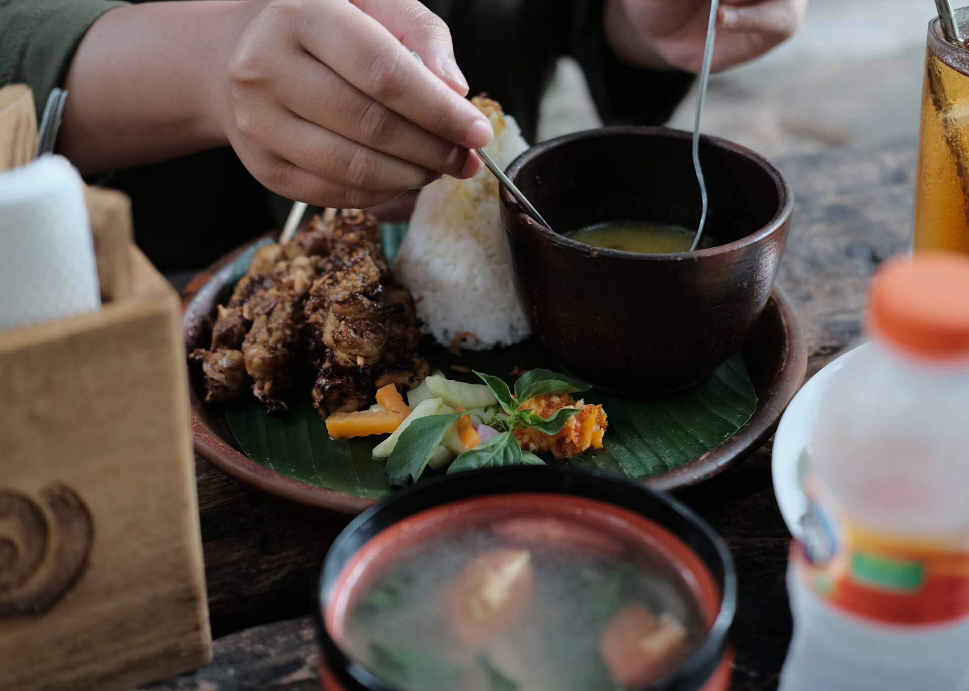 Traditional Indonesian nasi with sate, soup and sambal on banana leaf